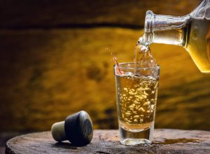 Glass of golden rum, with bottle. Bottle pouring alcohol into a small glass. Brazilian export type drink