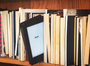 Wooden bookcase with e book reader amid classic books